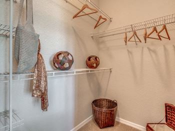 Furnished model walk in closet with bins, hangers and hamper